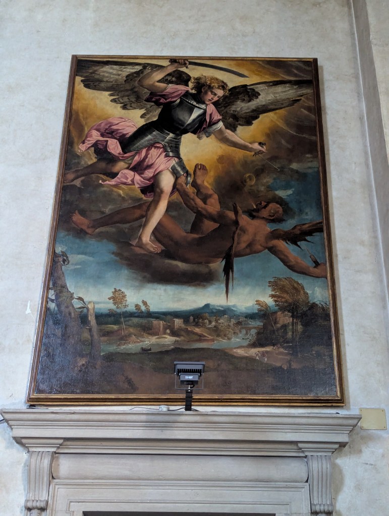 A large painting depicting Archangel Michael defeating a demon, with dramatic clouds and a landscape in the background.